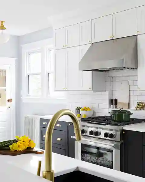Crystal Cabinet Works frameless Stirling cabinets with Simply White uppers contrasted with Black base cabinets and white subway tile splash in this remodeled  kitchen