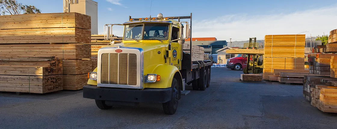 Yellow lumber delivery truck leaves South City Lumber & Supply lumber yard in South San Francisco