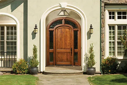 The unique arched-top and transom surround of this Rogue Valley custom wood front entry door complements the curved entryway of this upscale home